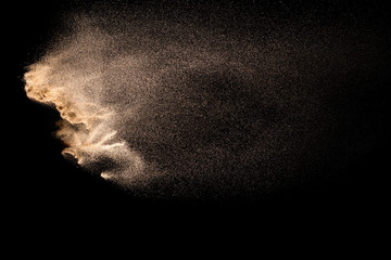 Golden sand explosion isolated on black background. Abstract sand cloud. Golden colored sand splash...