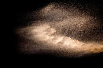 Golden sand explosion isolated on black background. Abstract sand cloud. Golden colored sand splash against dark background. Yellow sand fly wave in the air.