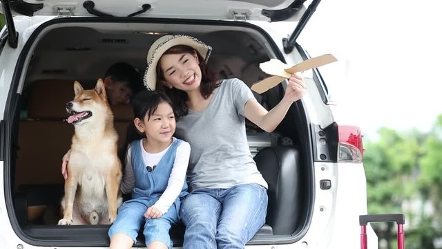Pet lover An Asian family with a mother, daughter, and son having a view on the van. Mom and Child are playing paper plane on a car with a beautiful view.