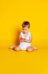 Naklejka premium little boy in a t-shirt and underwear sitting on an orange-yellow background