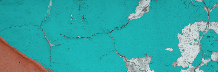Obraz premium Peeling paint on the wall. Panorama of a concrete wall with old cracked flaking paint. Weathered rough painted surface with patterns of cracks and peeling. Panoramic texture for background and design.