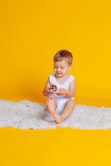little boy in a t-shirt and underpants on an orange-yellow background with a Christmas ball in his hand