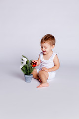 one year old baby tries to decorate the Christmas tree with a Christmas toy