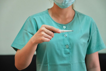 A female nurse with a digital  thermometer in her hand