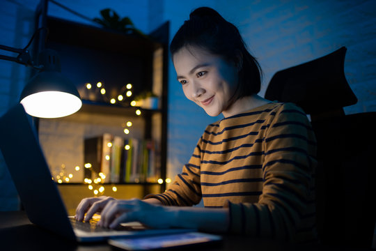 Asian Woman Happy Smiling Working On A Laptop At The Night At Home. WFH. Work From Home Avoid COVID 19 Concept.