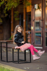 girl in a leather jacket waving legs on a bench