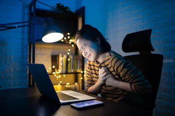 Asian woman was sick with chest pain working on a laptop overtime at home. WFH. Work from home for avoid the Coronavirus COVID 19 concept.