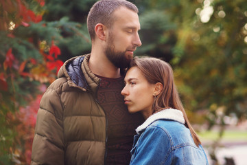 Young couple in love on romantic date in autumn park. Against backdrop of colorful autumn foliage. Lovers fall background. Leisure together. Young people.