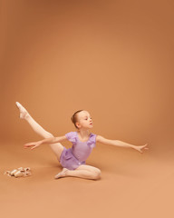 cute girl in a purple dress shows elements of ballet
