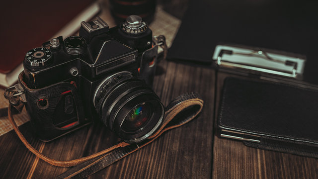 old camera and stationery lie on a wooden table, still life for the photographer’s site