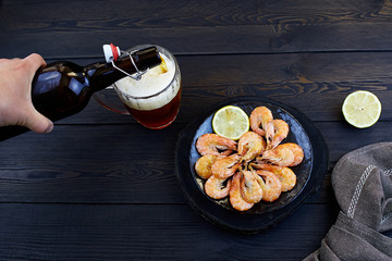 Red irish ale with shrimps on dark rustic wooden background. Homemade beer.