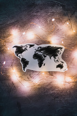 Fototapeta premium world map surrounded by fairy lights on concrete desk