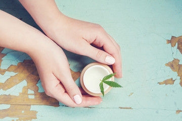 Cannabis cream with marijuana leaf in hands. Concept of herbal alternative medicine, cbd oil,...
