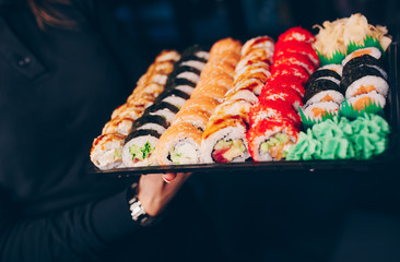 Hand Waiter holding Set Delicious fresh Sushi slate plate Sushi Rolls Warm Ebi Sake Unagi, Japanese raw fish in traditional restaurant. Philadelphia flesh Rolls served Japan bar.   