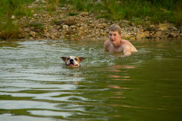 Selective focus. Man and his dog swimming and playing in the lake. 