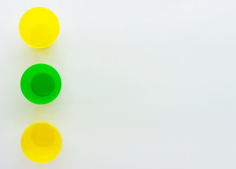 Colorful plastic cups, the view from the top. Yellow and green glass. Composition of plastic dishes. Minimalistic design with space for text. Isolated on a white background.