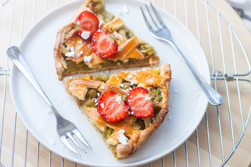 Slices of strawberry and rhubarb pie on white plate. Top view. Homemade summer bakery.