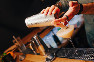 Bartender pouring using strainer White healthy Cocktail drink on a bar counter . Professional view . Trendy stylish alcoholic drink .  Design people and luxury concept service barman in nightclub