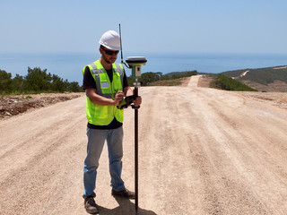 Geodetic engineer surveyor in white hard hat doing measurements with GNSS satellite receiver