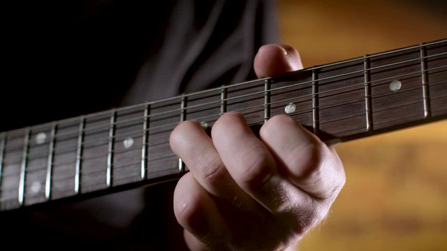 Guitar player plays blues style solo on electric guitar, closeup on neck