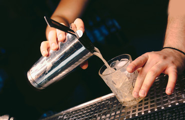 Bartender pouring using strainer White healthy Cocktail drink on a bar counter . Professional view...