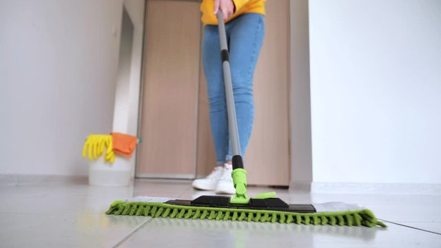 young woman washing white kitchen floor with special swob, cleaning service, close-up