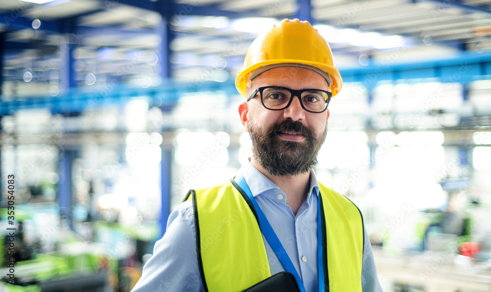 Wall mural front view of technician or engineer with hard hat standing in industrial factory.