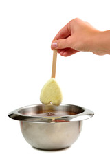 Hand dipping vanilla ice cream in heart shape on wooden stick in hot liquid dark chocolate