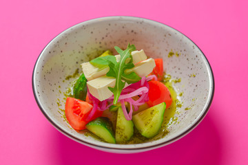 Healthy organic vegan vegetable salad served in a bowl over bright pink background. Spring seasonal concept.