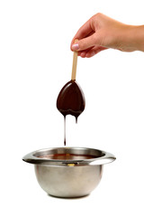 Hand dipping vanilla ice cream in heart shape on wooden stick in hot liquid dark chocolate