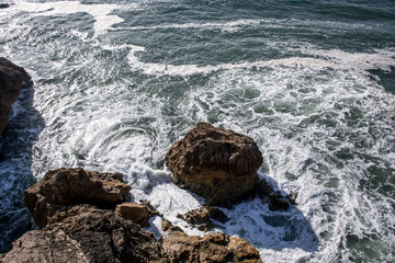 Sea wave on the stones, foamy spray, summer landscape.