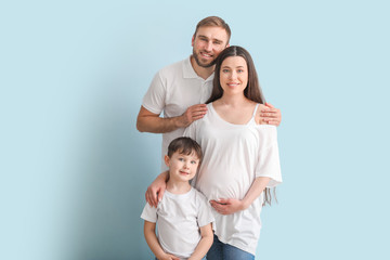 Beautiful pregnant woman and her family on color background