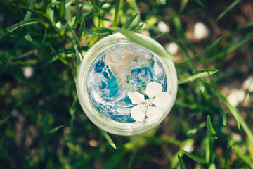 Planet Earth in glass on green grass background. World environment day concept. Elements of this...