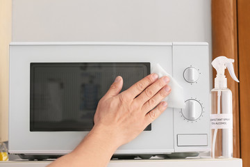 Man disinfecting microwave oven in kitchen