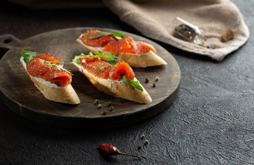 Homemade bruschetta with salmon,cherry tomatoes,fresh arugula and dried pepper.Close up.