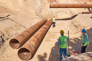 Workers are laying metal culverts under the highway under construction