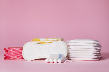 stack of menstrual sanitary cotton pads and tampon on pink background. Feminine hygiene products....