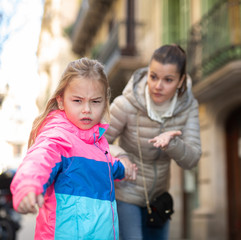 Angry naughty girl with worried mother outdoors