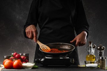 Chef fries tomato paste for making sauce. Culinary recipes. Restaurant business, delicious and healthy nutrition.
