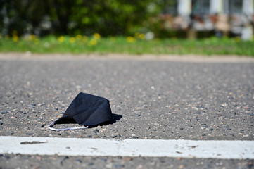 Photo of a protective black mask lying on the pavement during a virus outbreak
