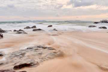 Fototapeta na wymiar a wavy sea with rocks near a beach.