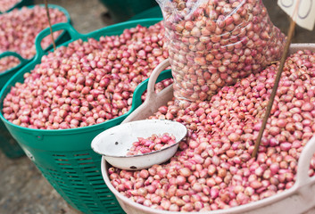 Large baskets of many small red onions at the local farmers market in Thailand.