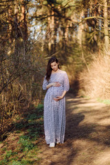 Young pregnant woman relaxing in park outdoors