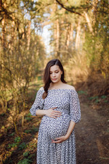 Young pregnant woman relaxing in park outdoors