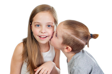 Young smiling caucasian girl and boy kisses her on the cheek isolated on white background