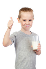 Young smiling caucasian boy with milky moustache holds glass and shows thumbs up of milk isolated on white background - 353064601