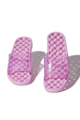 Detailed shot of pink massage sandals with knobby balls on the soles and with wide clear straps. The pair of footwear for foot pain treatment is isolated on the white background. 