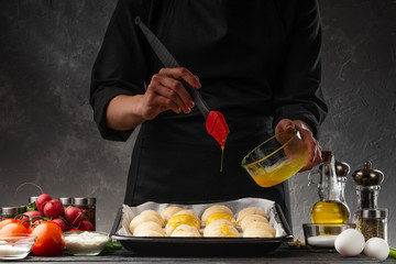 A baker prepares buns for baking, spreading with an egg, a bakery and cooking buns. baking