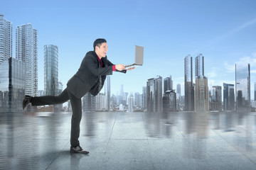 Asian businessman standing and reading news on his laptop