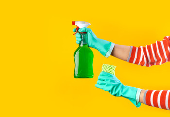 Female hands in green gloves holding rag and spray detergent